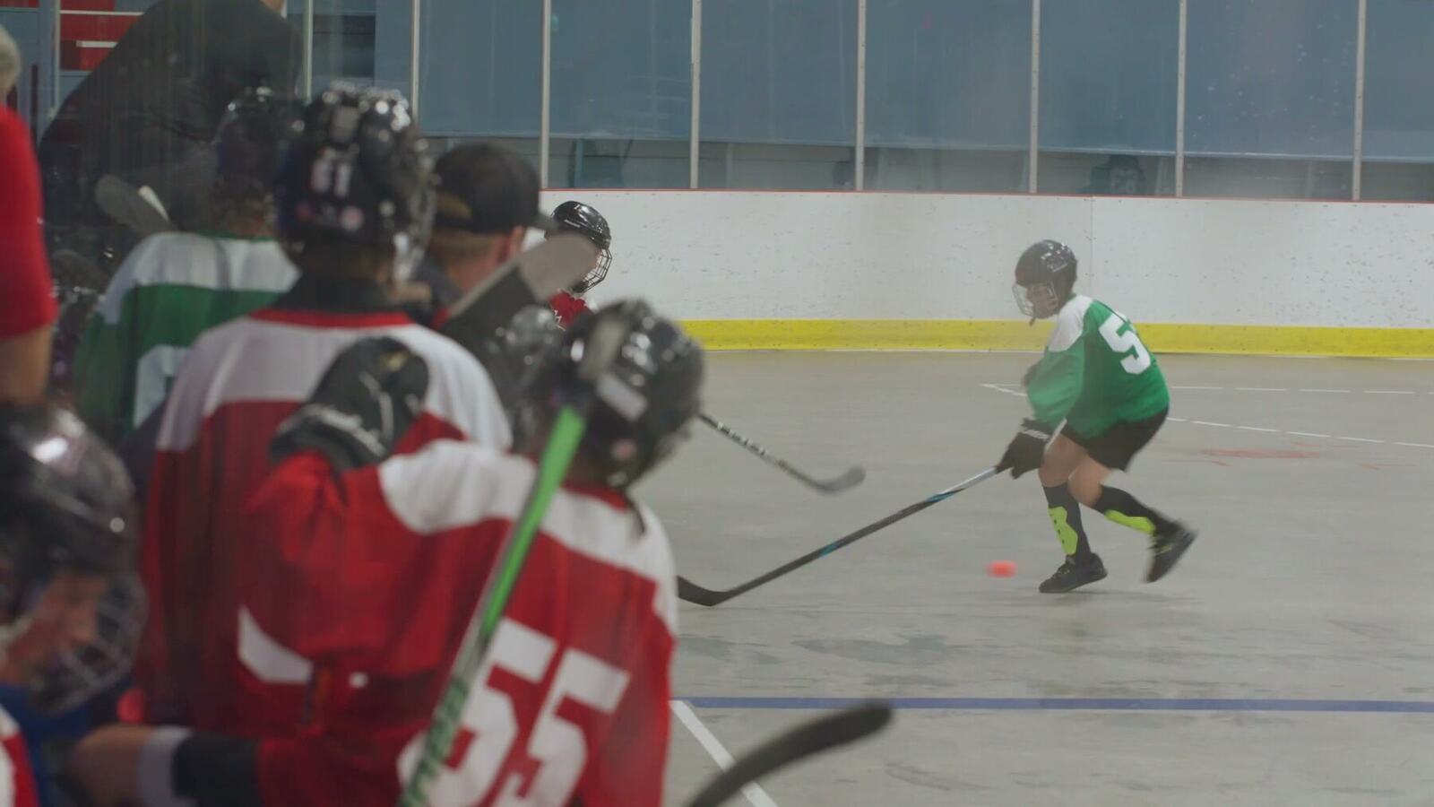 Youth ball hockey action filmed through arena glass