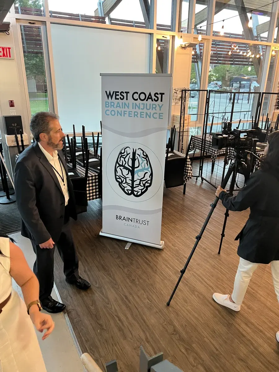 Camera setup beside BrainTrust Canada's West Coast Brain Injury Conference banner