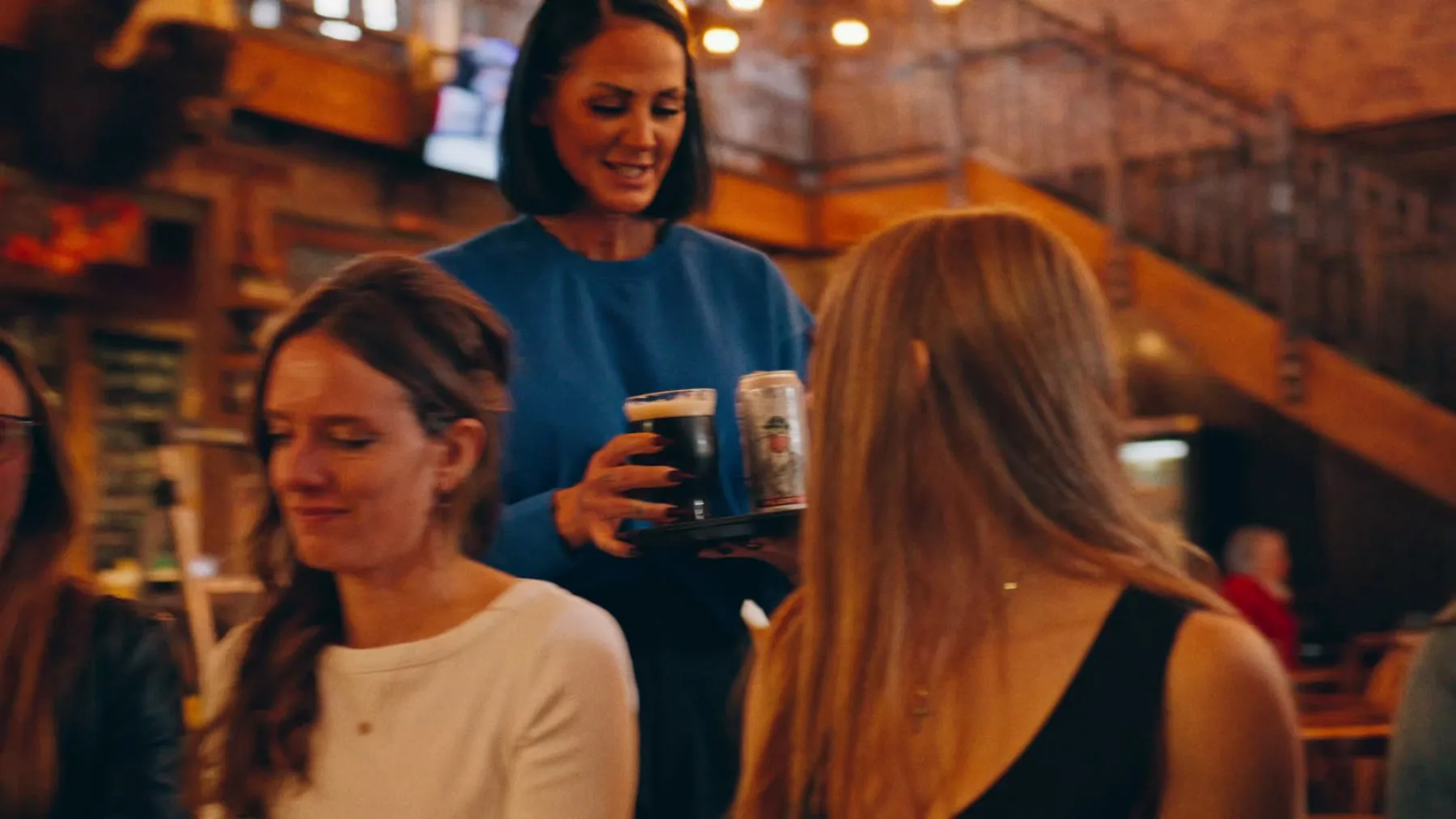 Server carrying drinks through a warm restaurant interior in the Jason Parkes Customs commercial