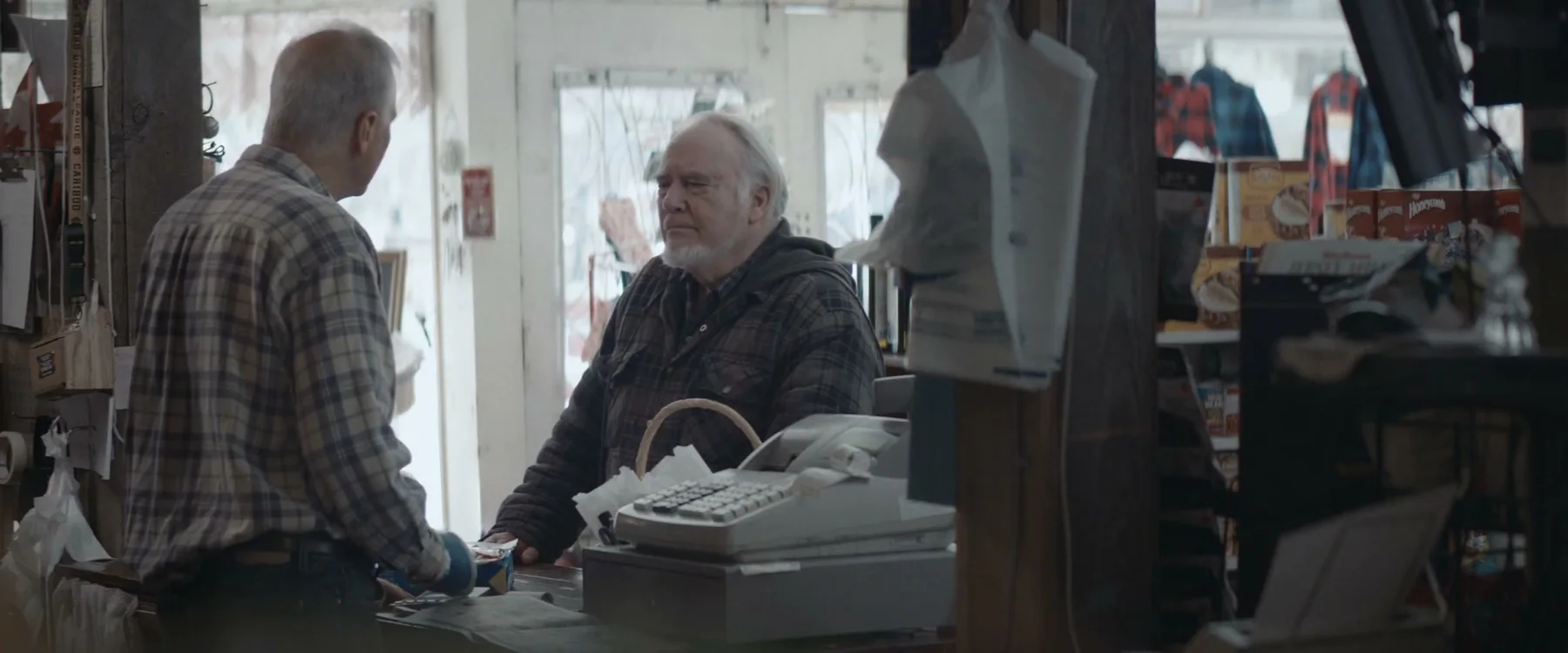 Two men facing each other across the general-store counter in Mabel
