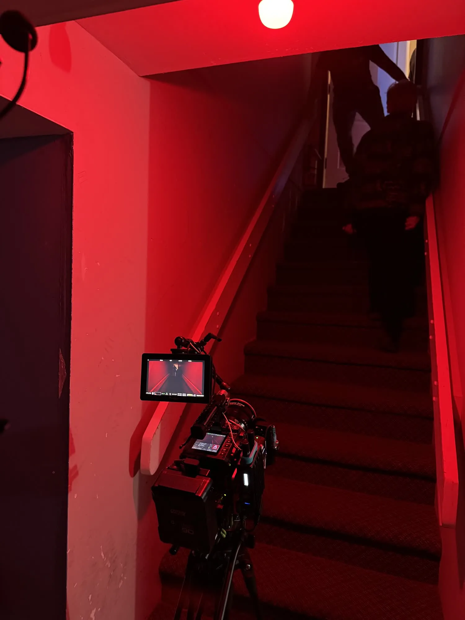 RED camera and lighting setup on a red-lit stairwell during Midlife Shuffle
