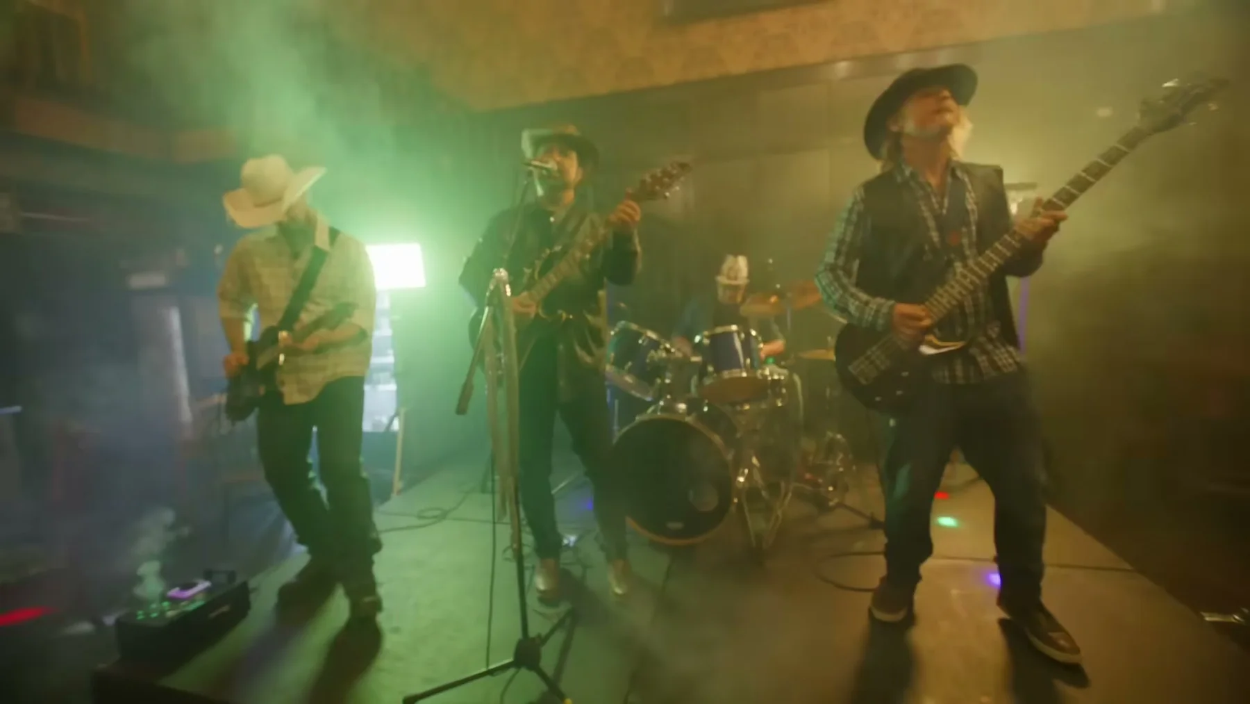 Kris Anders performing with the band under green and amber light in Open Road