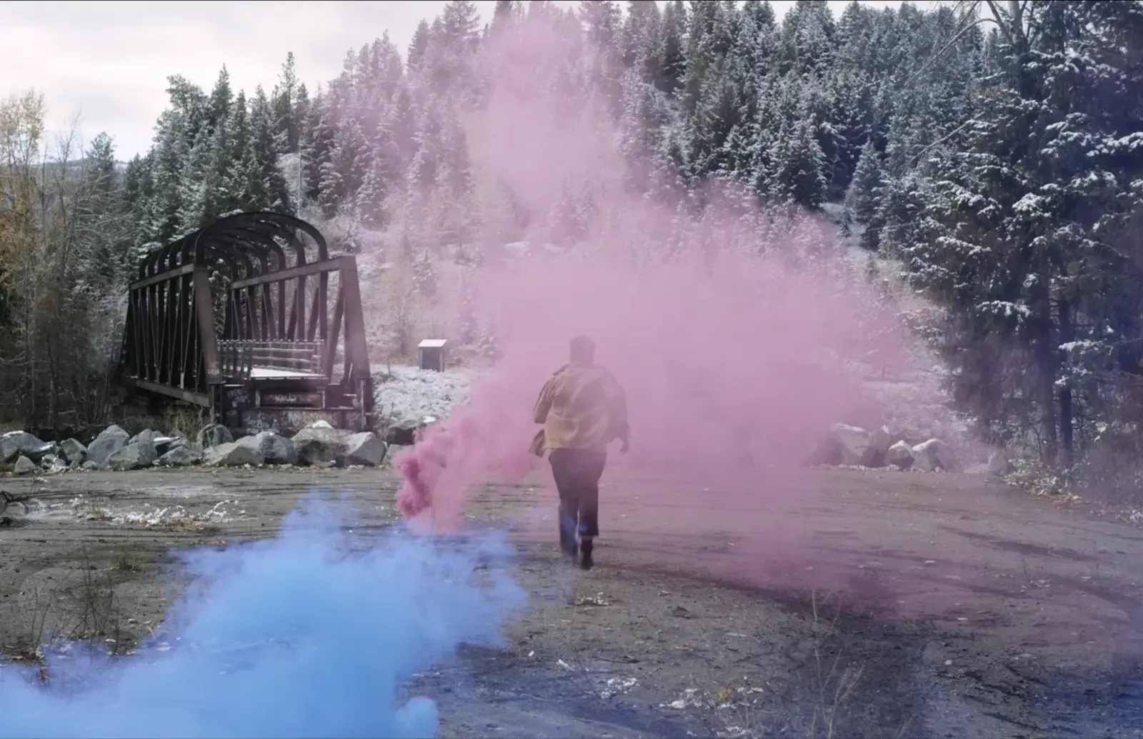 Performer moving through coloured smoke beside a Princeton bridge