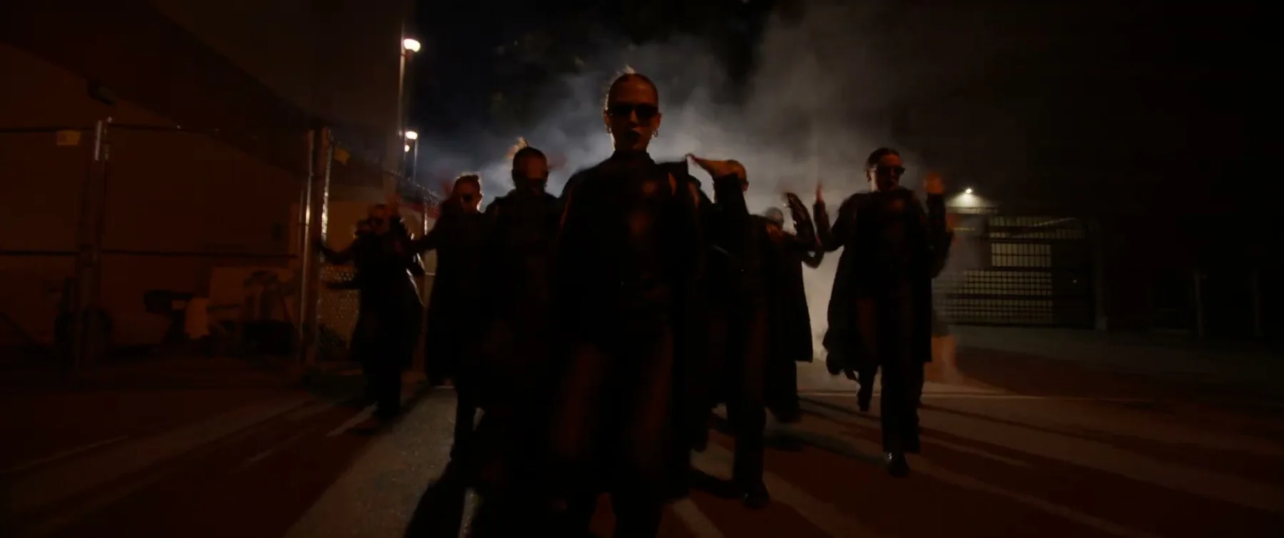 Sockeye ensemble walking toward camera through smoke at night in the 2025 film